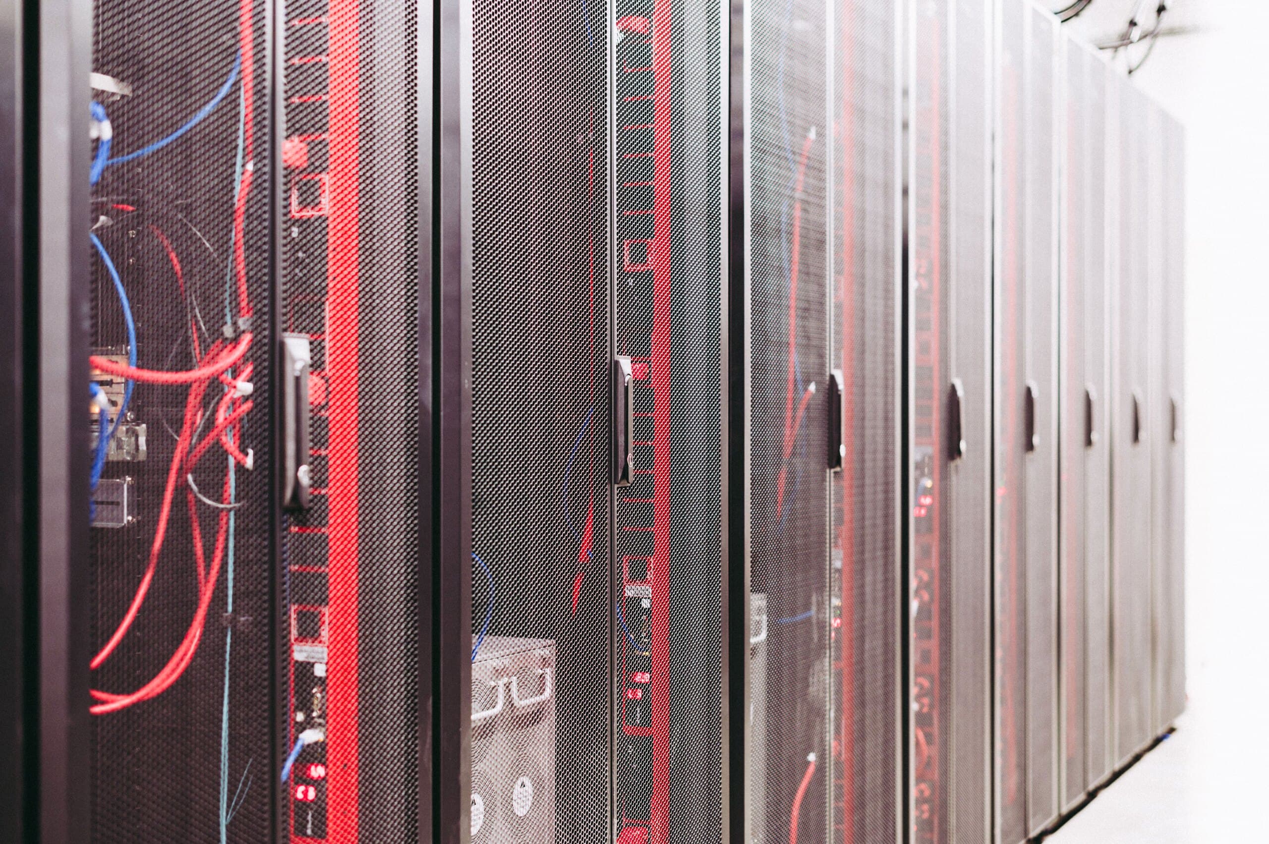 A row of server cabinets with power distribution units behind mesh doors